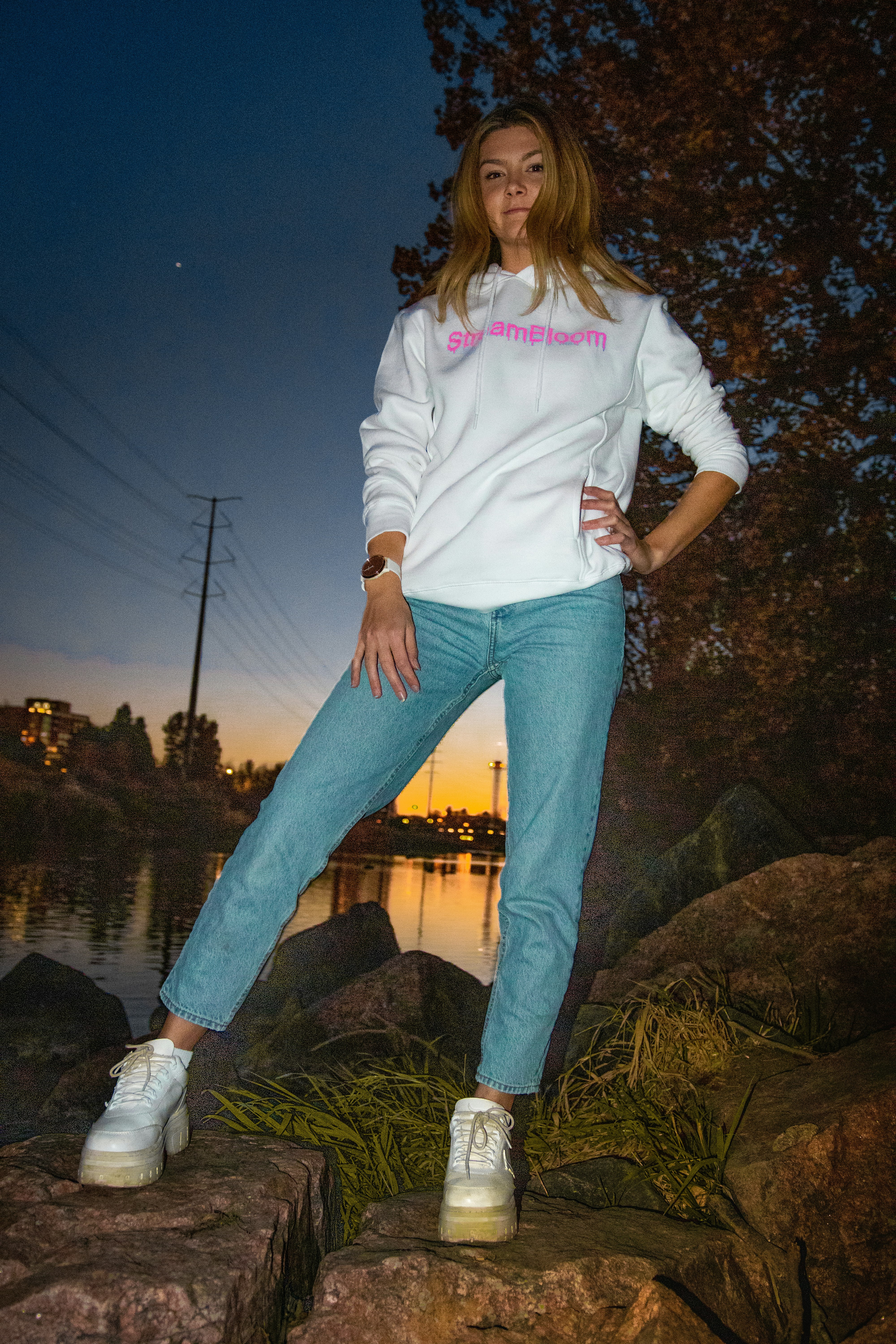 woman in white long sleeve shirt and blue denim jeans standing on brown rock near body