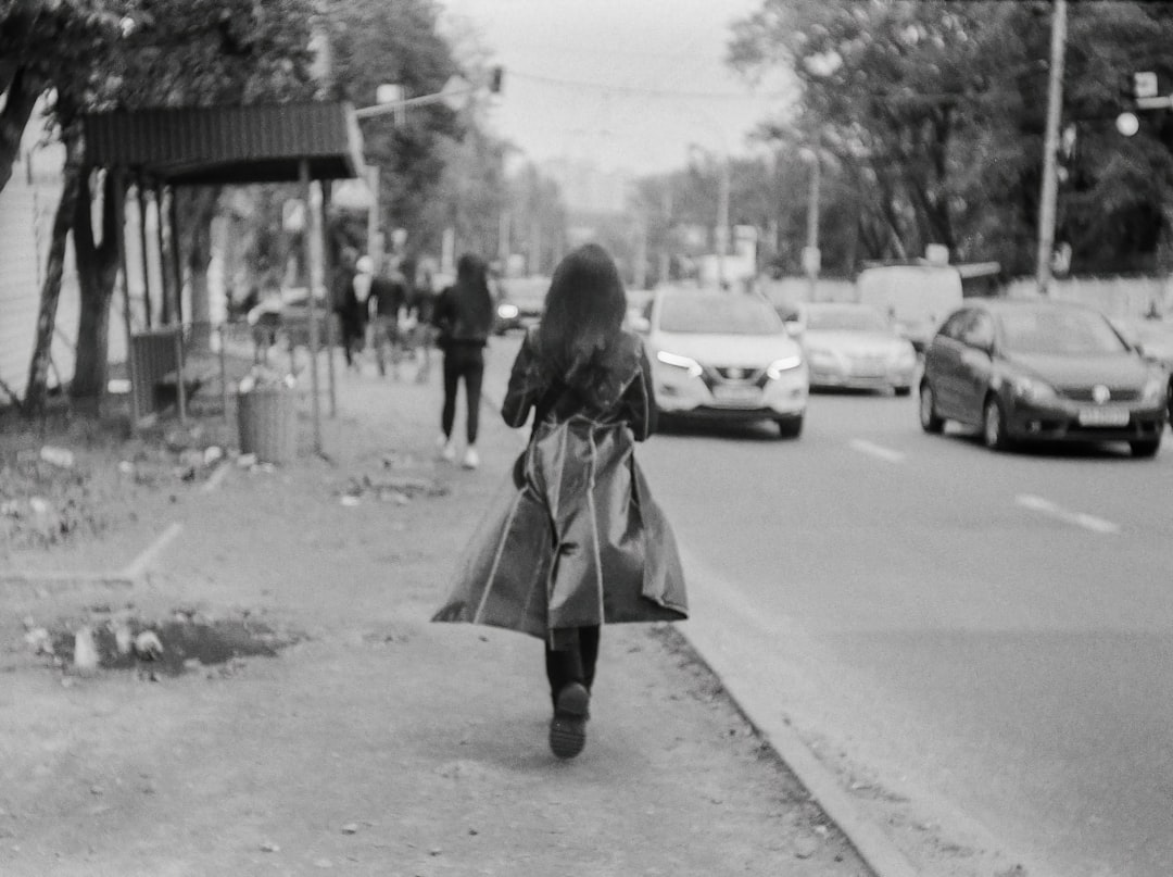 woman in black coat walking on sidewalk during daytime