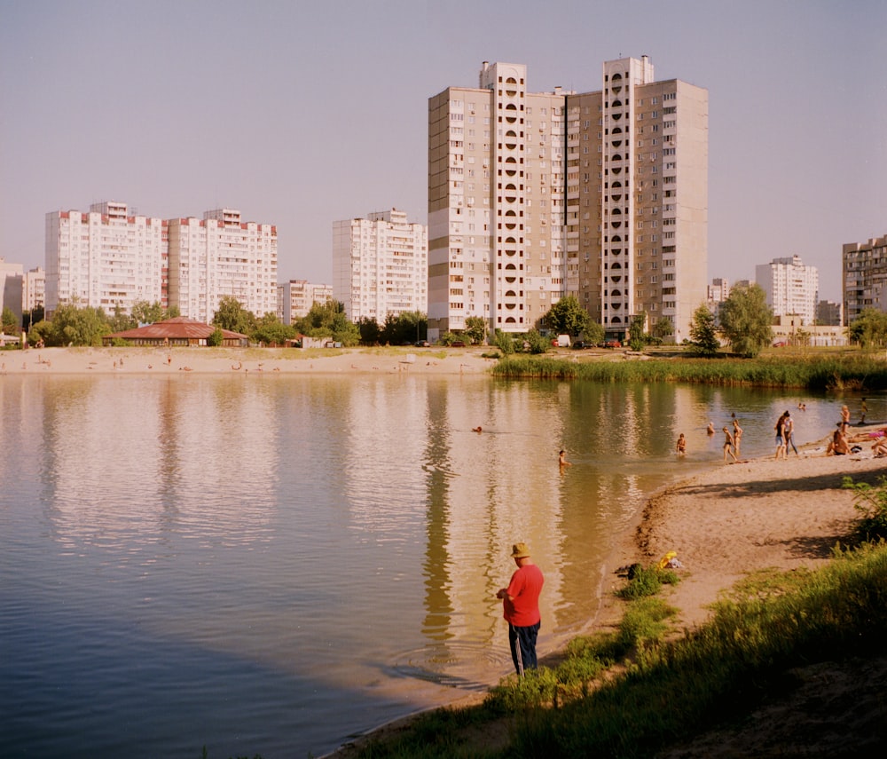 woman in red jacket walking on green grass near body of water during daytime