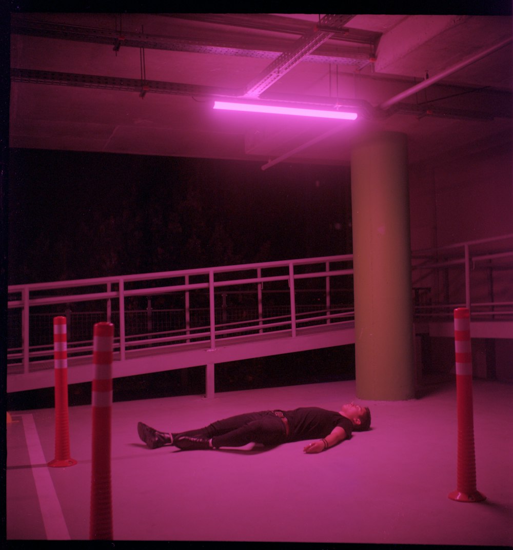 man in black leather jacket and black pants lying on white metal bar