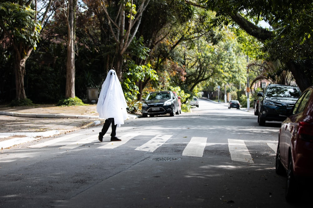 femme en robe blanche marchant dans la rue pendant la journée