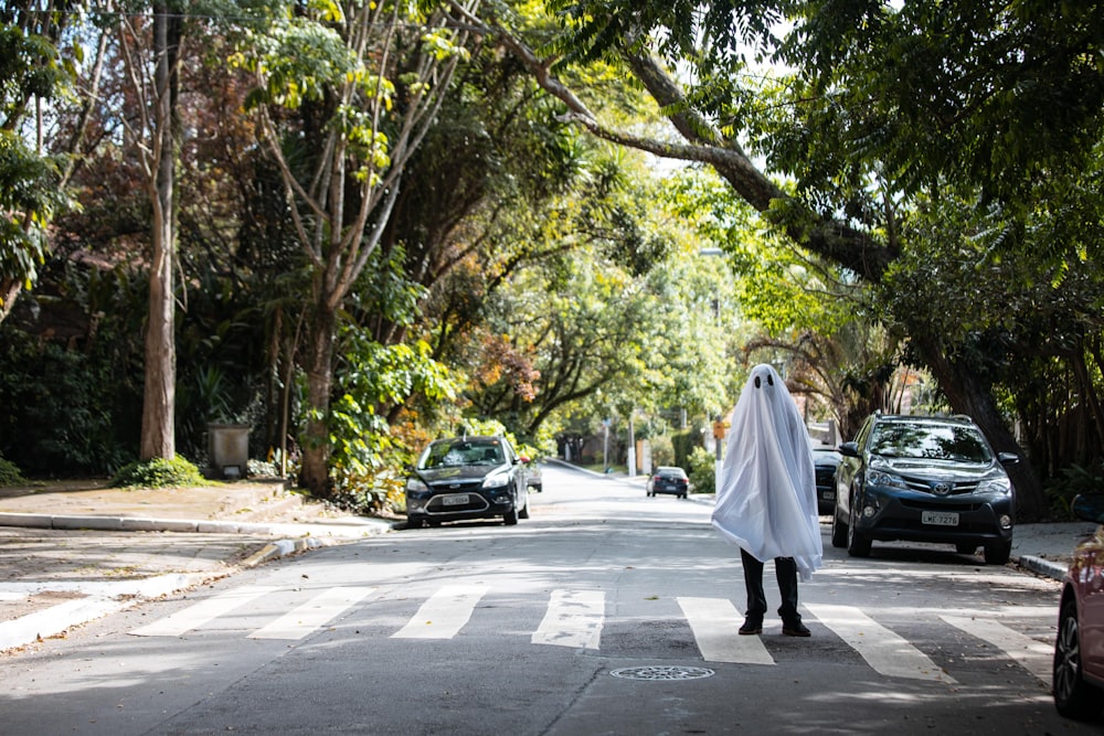 homem em thobe branco andando na rua durante o dia