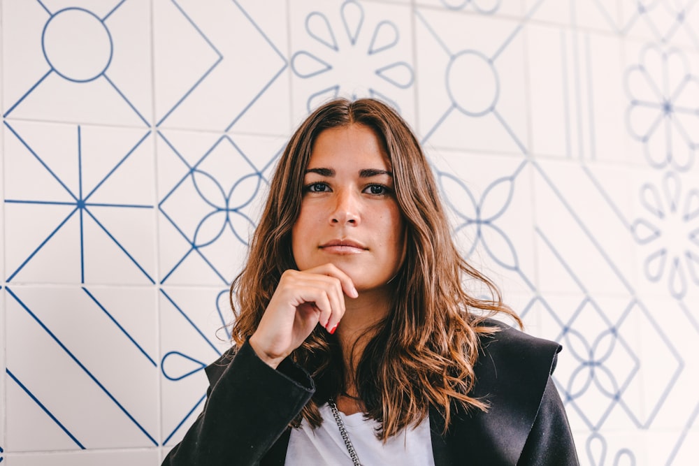 Mujer con blazer negro cubriendo su rostro con la mano