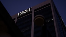A tall office building under a dark sky, prominently featuring the letters 'BB&T' at the top. The structure is designed with large glass windows and concrete frameworks, creating a modern architectural appearance.