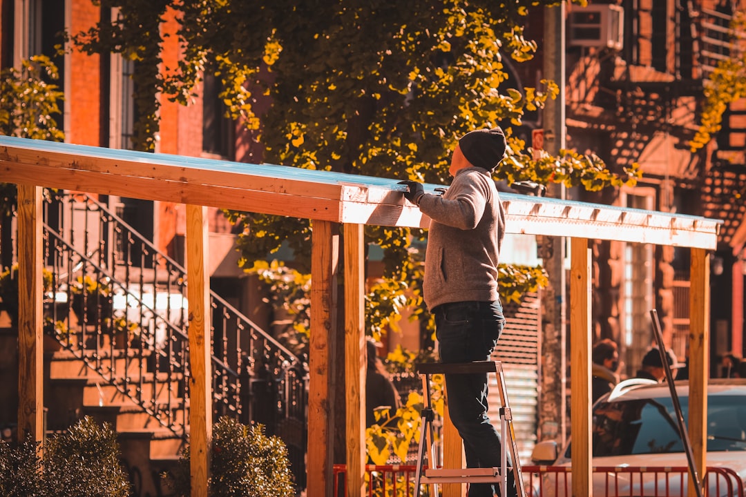 man in gray long sleeve shirt and black pants sitting on brown wooden bench during daytime