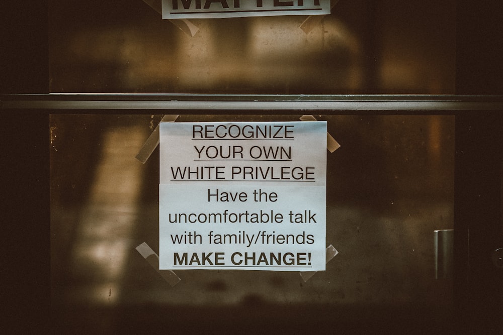 a sign on a door that says, recognize your own white privilege have the uncomfortable