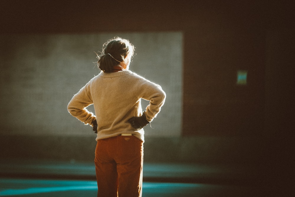 man in white sweater and brown pants standing on blue floor