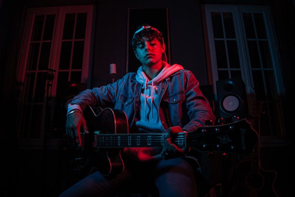 man in red and blue plaid dress shirt playing guitar