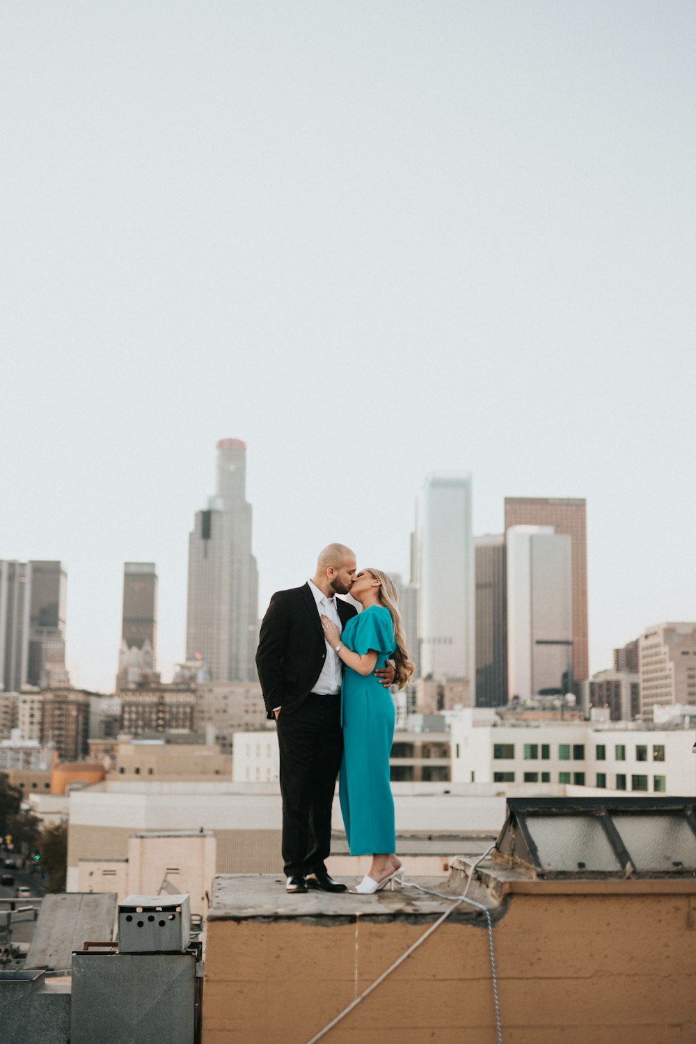 man in black suit jacket and blue dress shirt standing on roof top during daytime