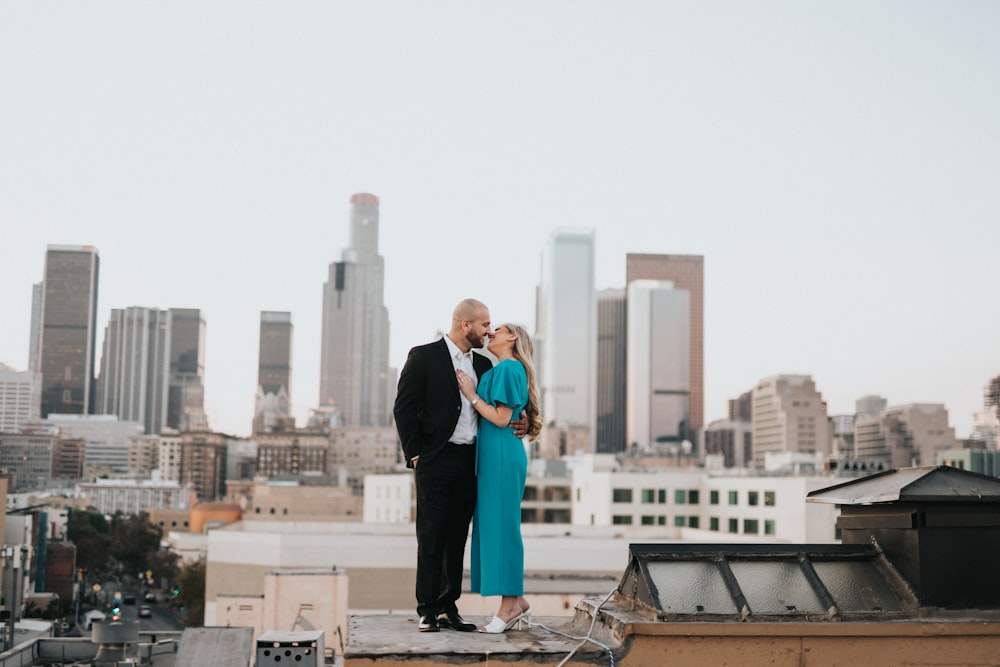 man in black suit jacket and woman in blue dress kissing during daytime