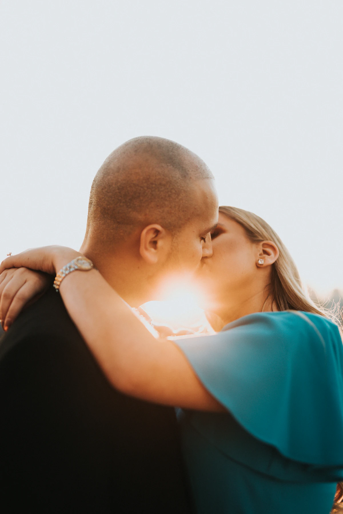man in blue shirt kissing woman in black shirt
