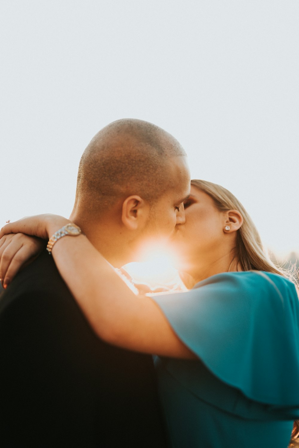 man in blue shirt kissing woman in black shirt