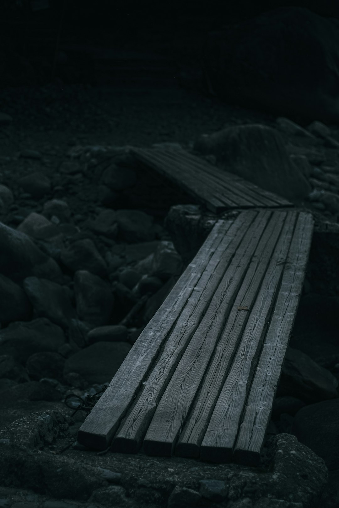 brown wooden bench on rocky ground