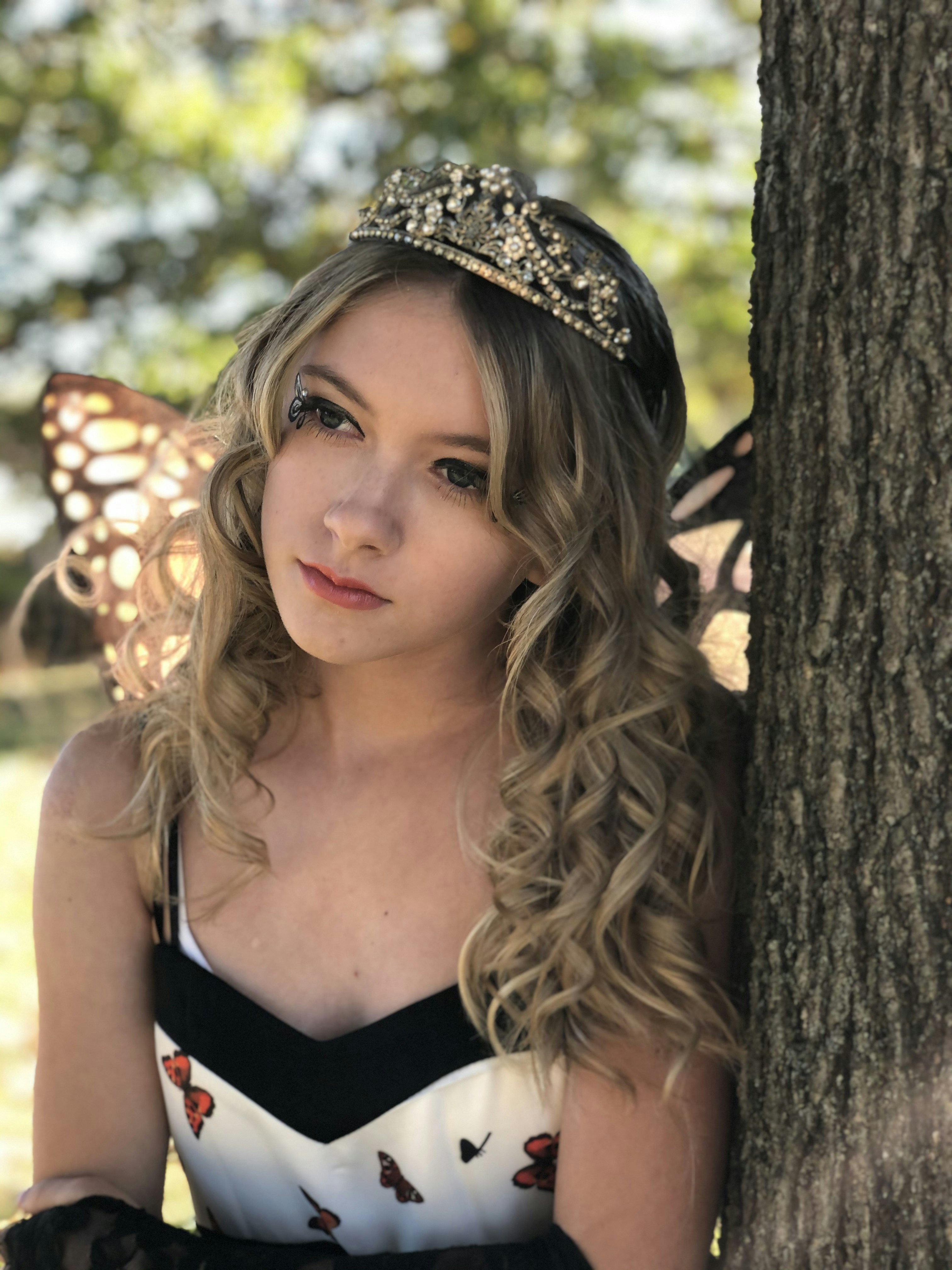 a girl going to her prom with a tiara and a blonde balayage hair color