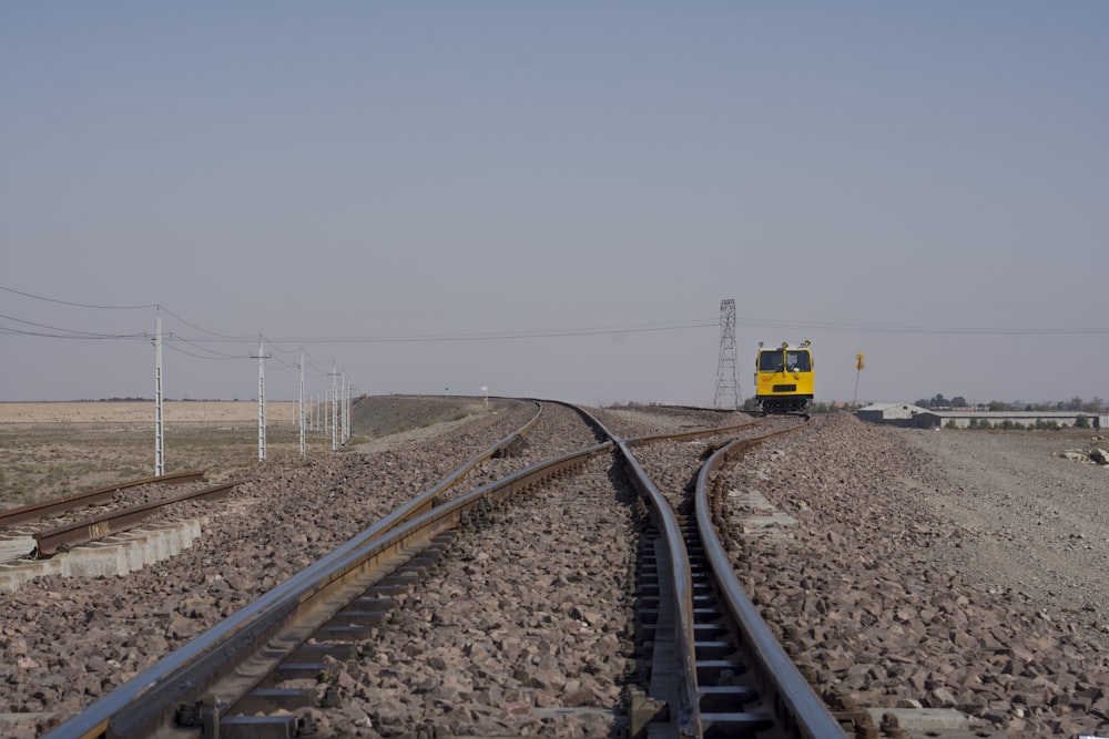 Gelber und schwarzer Zug auf Bahngleisen unter grauem Himmel