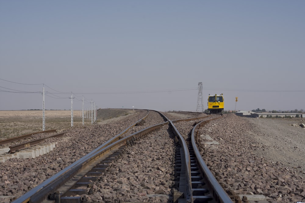 tren amarillo y negro en las vías del tren bajo el cielo gris