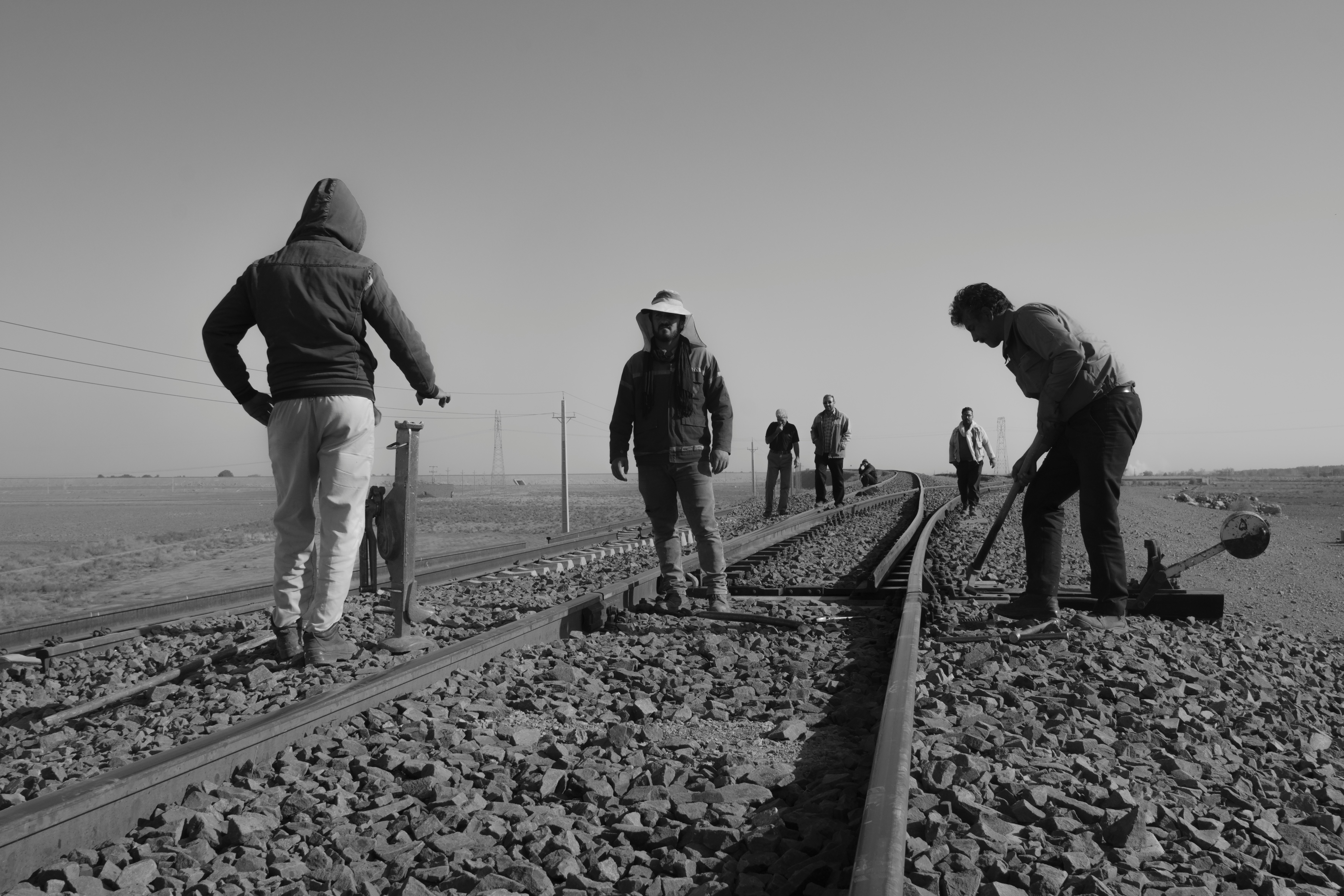 grayscale photo of people walking on train rail