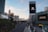 A view of a wide, empty city street lined with palm trees and modern buildings. Prominent buildings include a recognizable tower with a large digital sign displaying 'Caesars Entertainment' and another message 'We can't wait to welcome you back'. The street is well-maintained and devoid of traffic. The skyline features a mix of architecture styles with a clear blue sky.