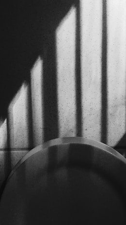 An artistic black and white frame showing shadows and light play on a textured wall.