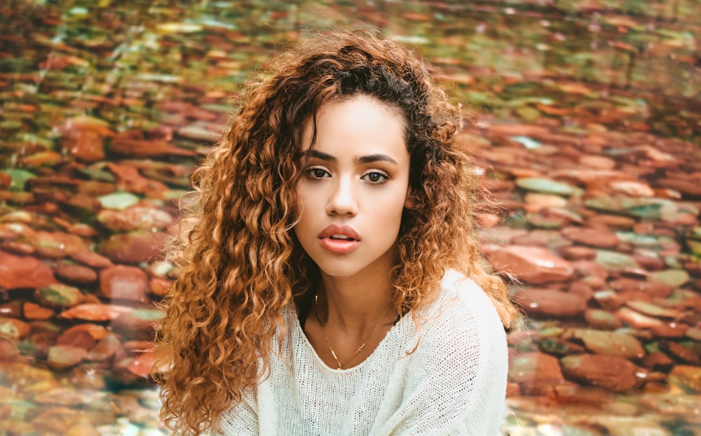 woman in white v neck shirt standing on brown leaves during daytime