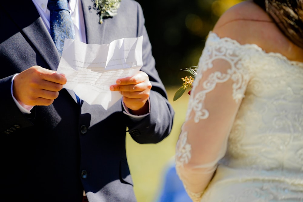 man in black suit holding womans hand