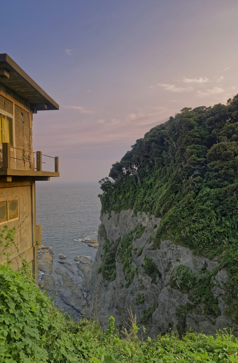 Casa de madera marrón en un acantilado junto al mar durante el día