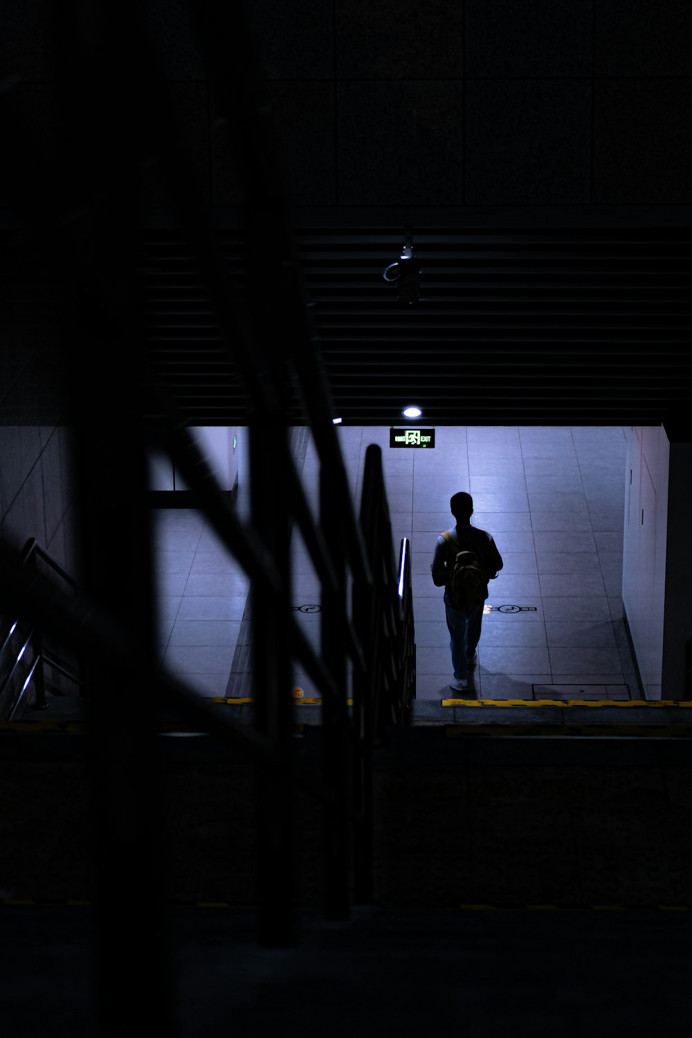 uomo in giacca nera che cammina sul corridoio