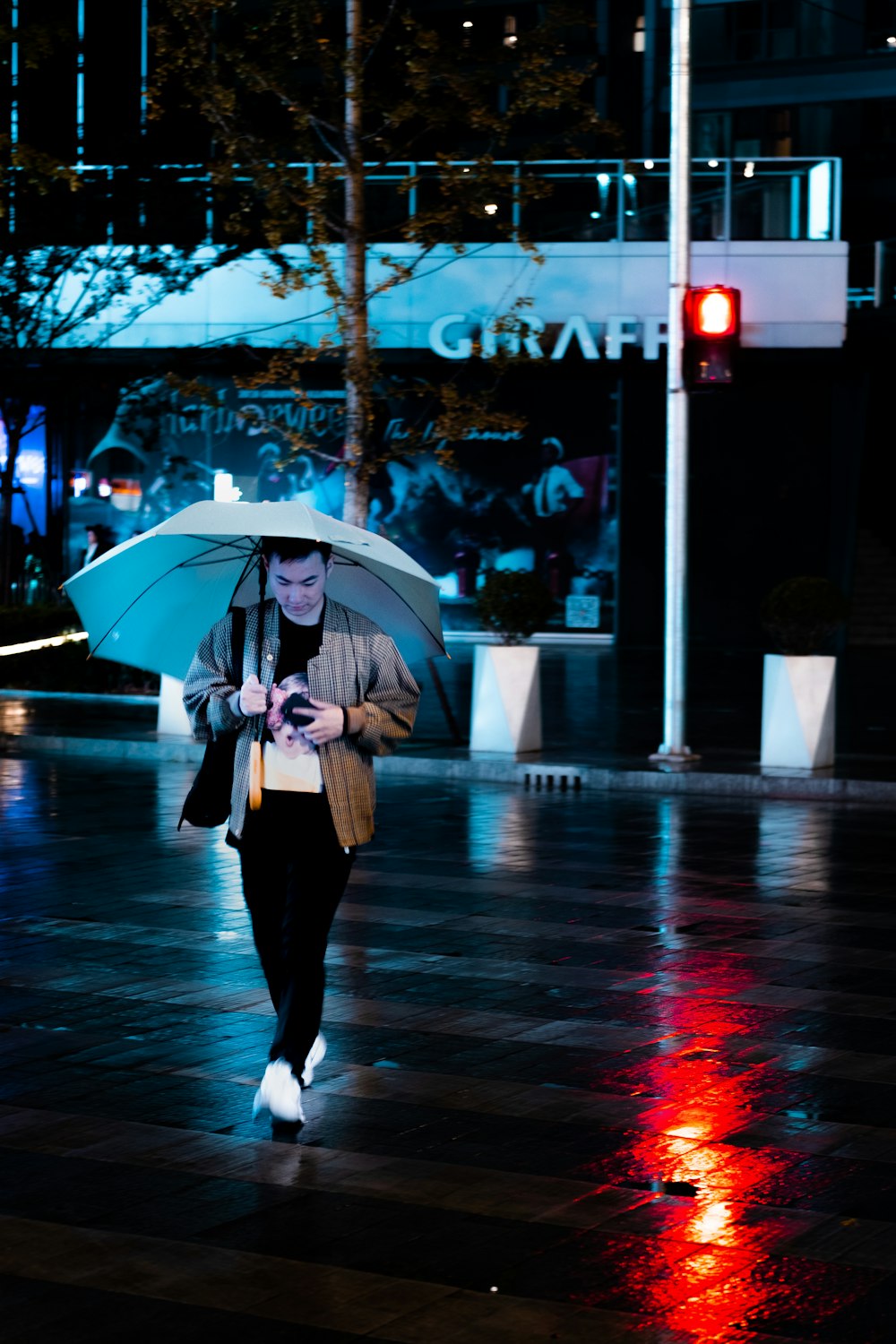Mujer con pantalones negros sosteniendo paraguas caminando por la calle durante el día