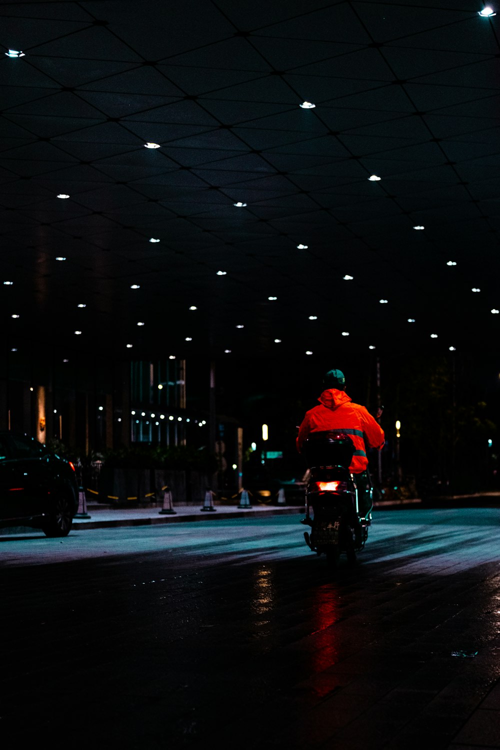 Hombre en chaqueta roja montando motocicleta en la carretera durante la noche