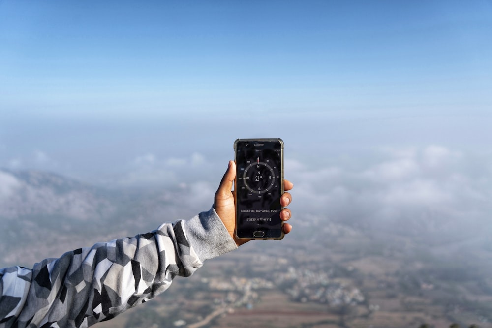 person holding black smartphone taking photo of blue sky during daytime
