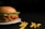 A crispy fried chicken sandwich with lettuce and tomato is placed on a white plate. Next to it, a few curly fries are scattered on a dark surface, creating a simple yet appetizing presentation.