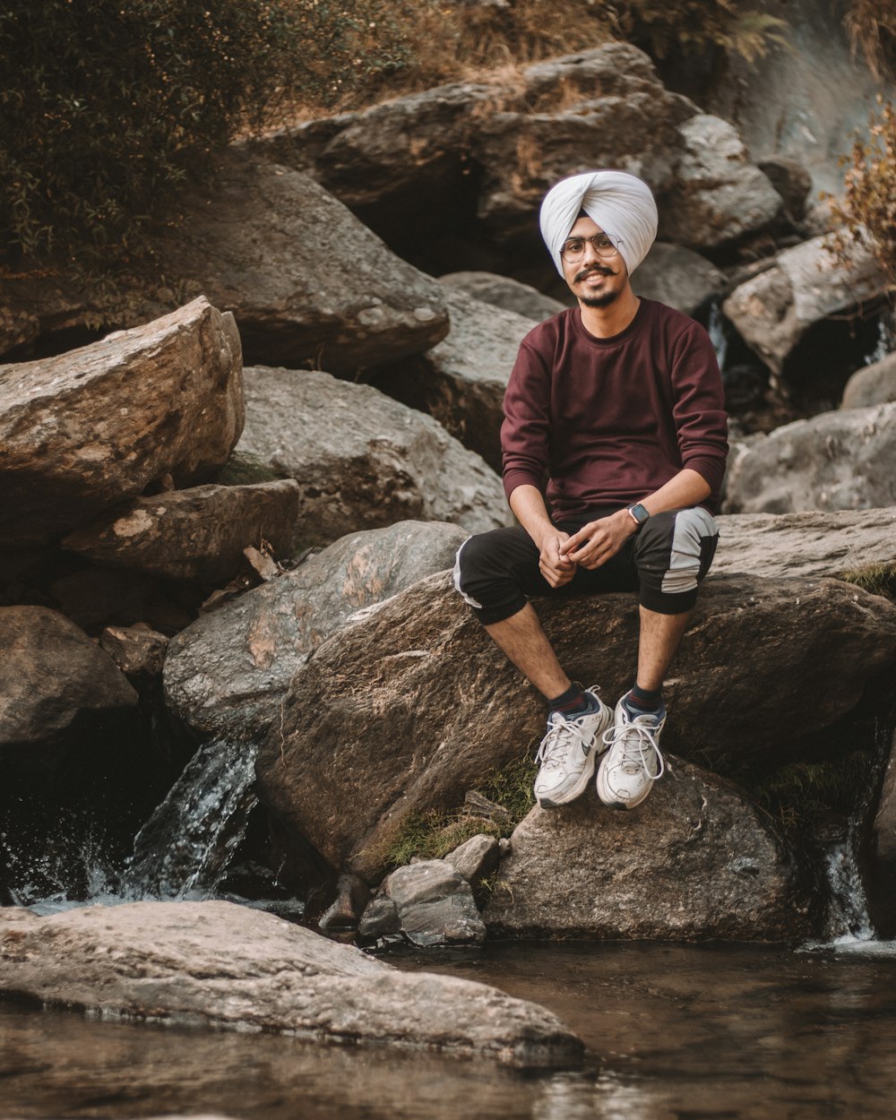 man in maroon sweater sitting on rock