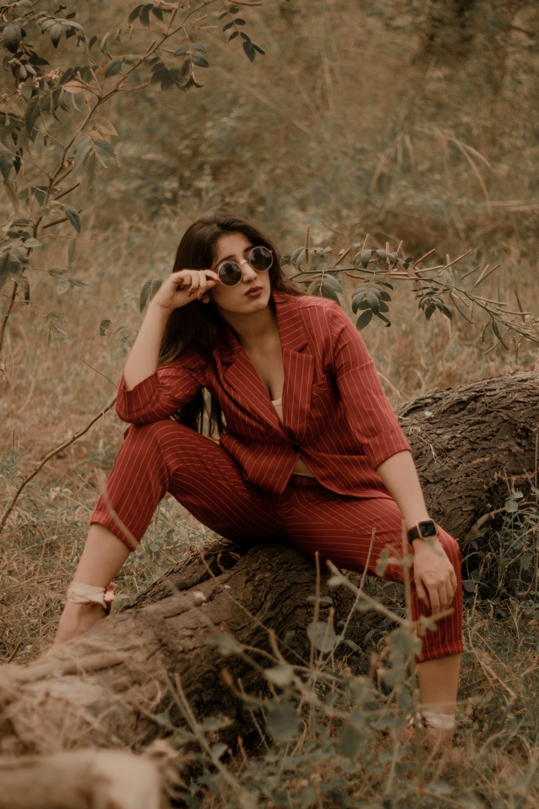 woman in red long sleeve shirt and red pants sitting on brown grass during daytime