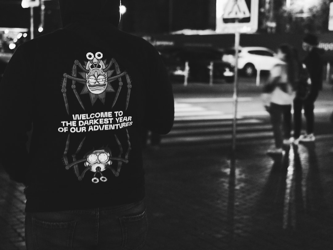 man in black and white crew neck shirt standing in grayscale photography