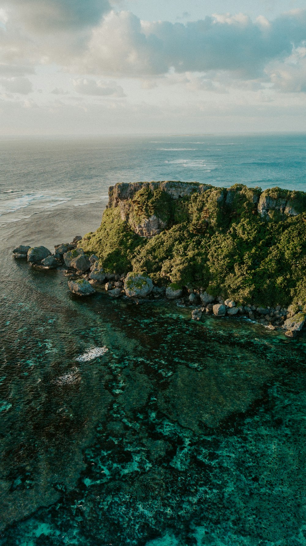 green and brown rock formation on sea water during daytime