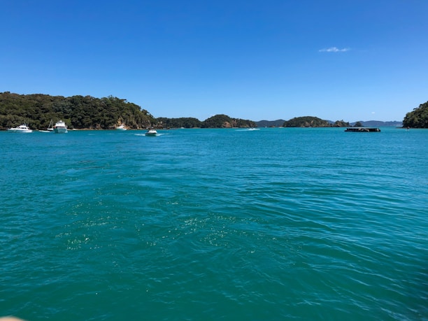 A serene view of a fastboat cruising over clear blue waters with lush islands in the background.