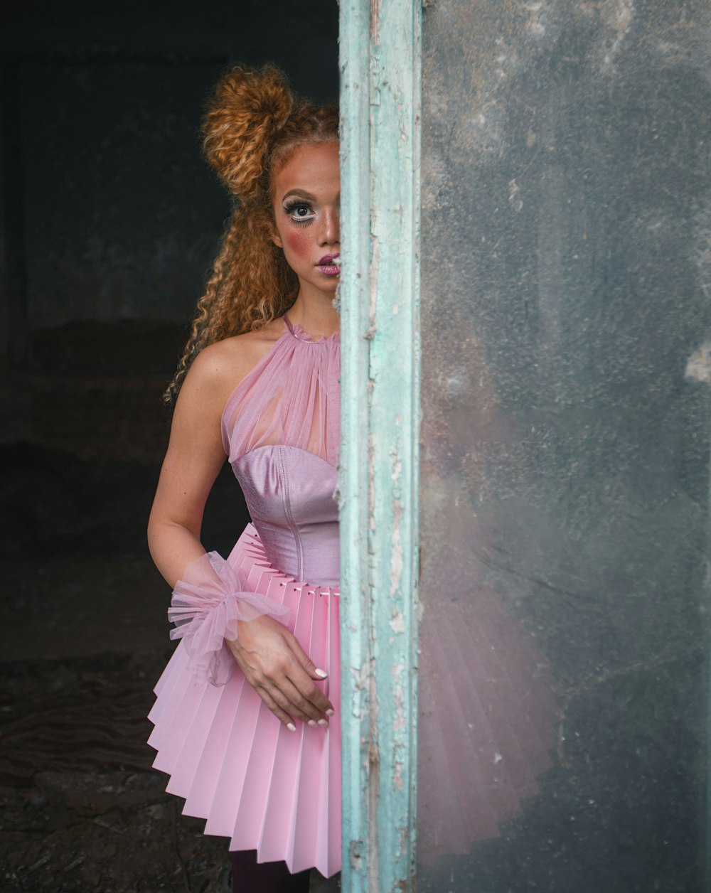 girl in pink dress leaning on blue wooden door