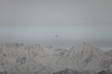 A scenic view of a small aircraft flying over mountains.