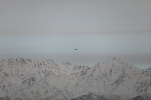 A scenic view of a small aircraft flying over mountains.