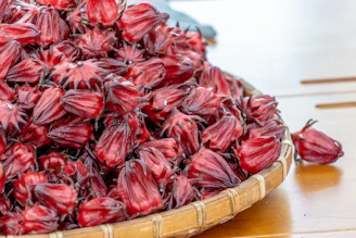 Heap of dried hibiscus flowers ready for export in colorful woven baskets.