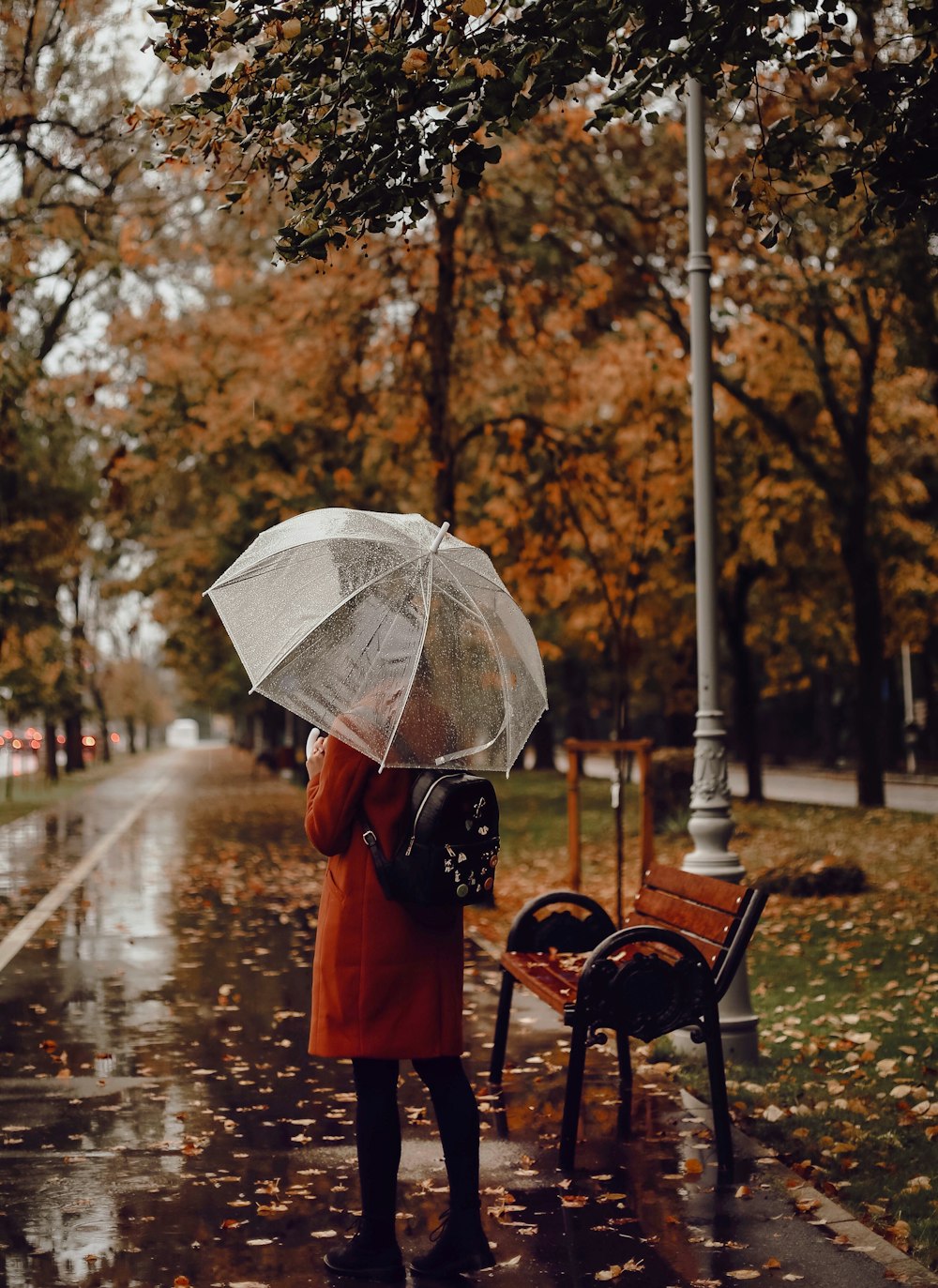 person in orange jacket holding umbrella