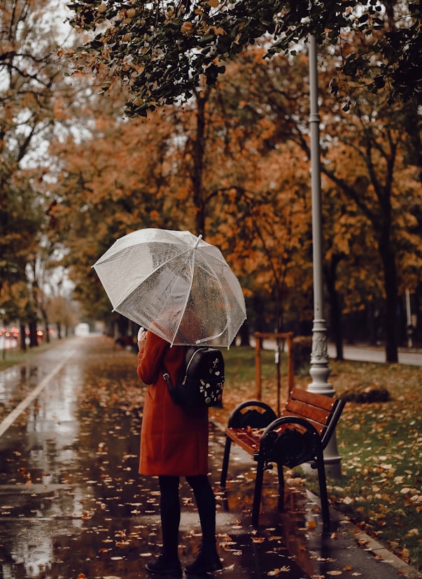 person in orange jacket holding umbrella