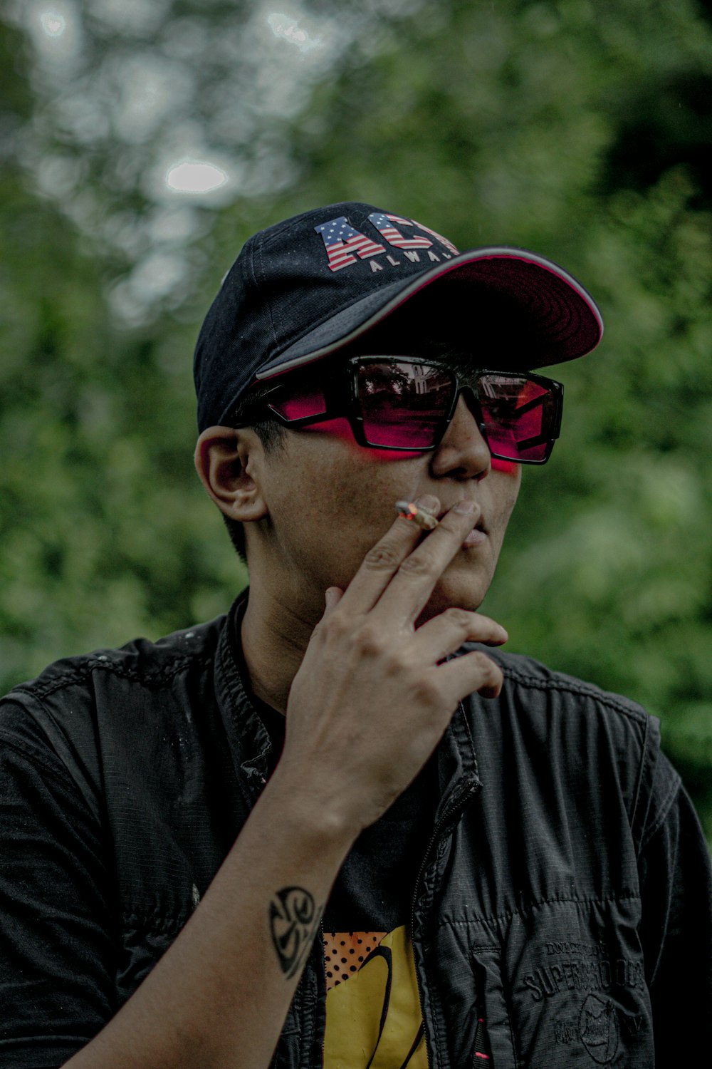 man in black leather jacket wearing black and red fitted cap