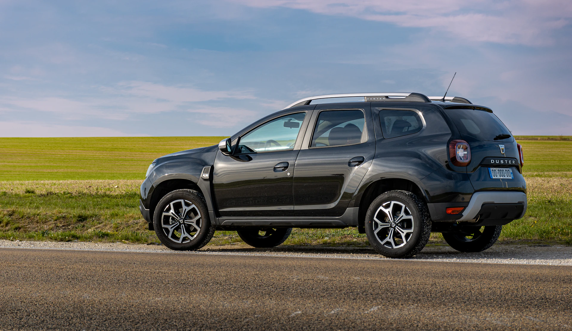 Dark Dacia Duster beside open fields