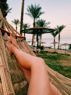Traveler relaxing in a hammock overlooking a pristine beach at sunrise.