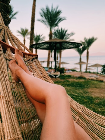 Traveler relaxing in a hammock overlooking a pristine beach at sunrise.