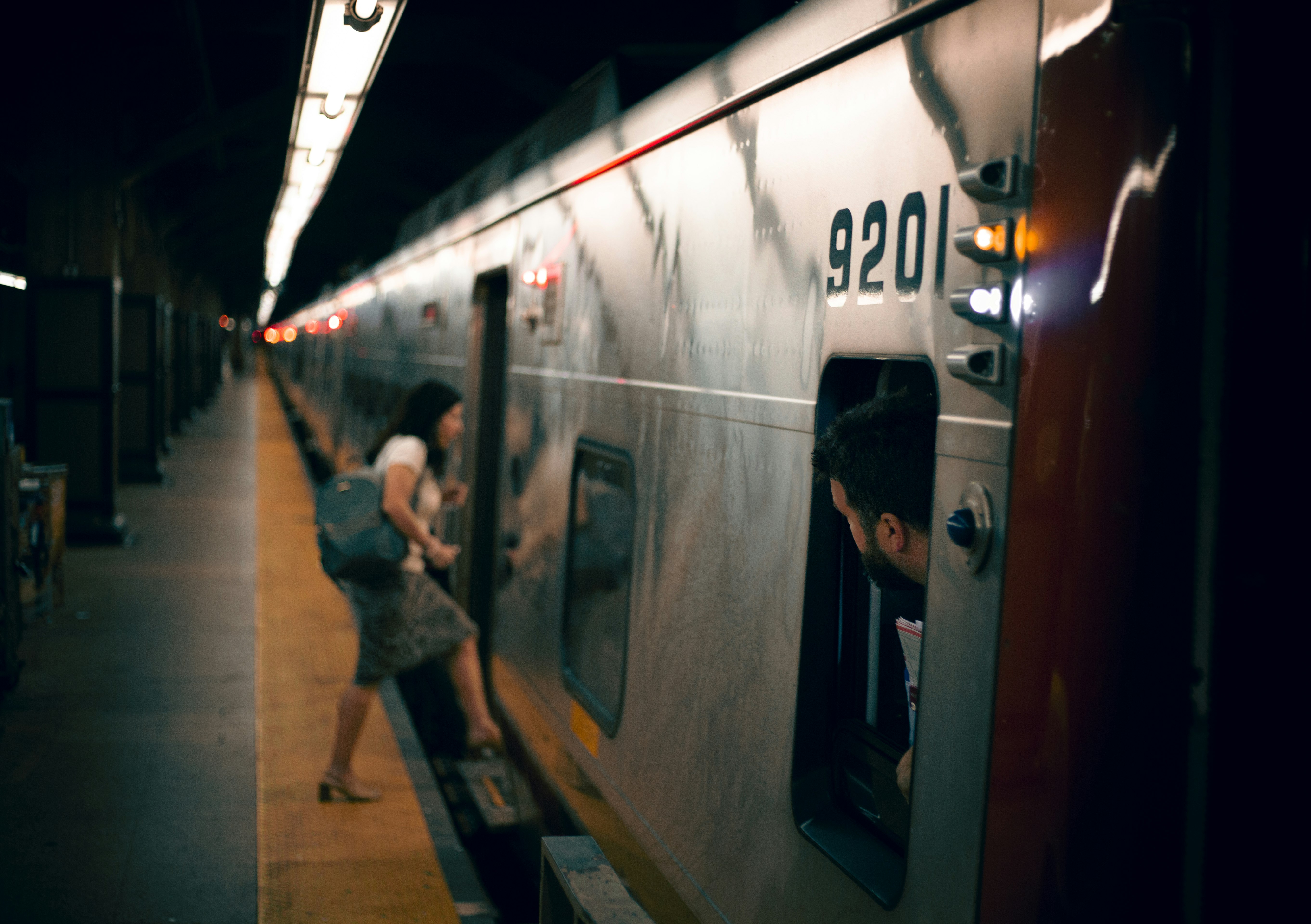 man in black jacket standing beside train