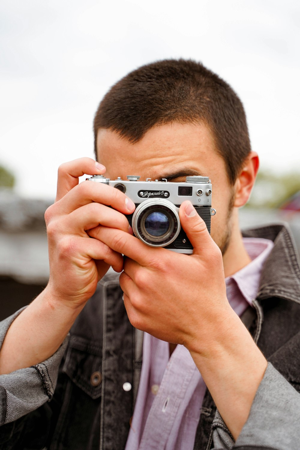 man in black and gray plaid dress shirt holding gray and black camera