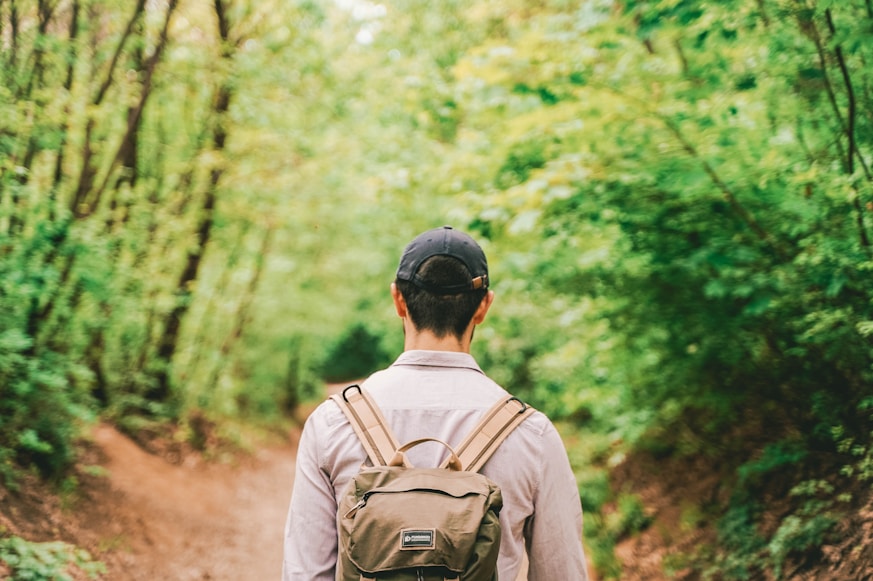 man in brown jacket wearing black helmet standing in forest during daytime