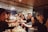 A group of people gathered in an office setting, holding glasses and toasting, creating a sense of celebration. They are standing around a table with plates and cups, displaying an atmosphere of camaraderie and joy.